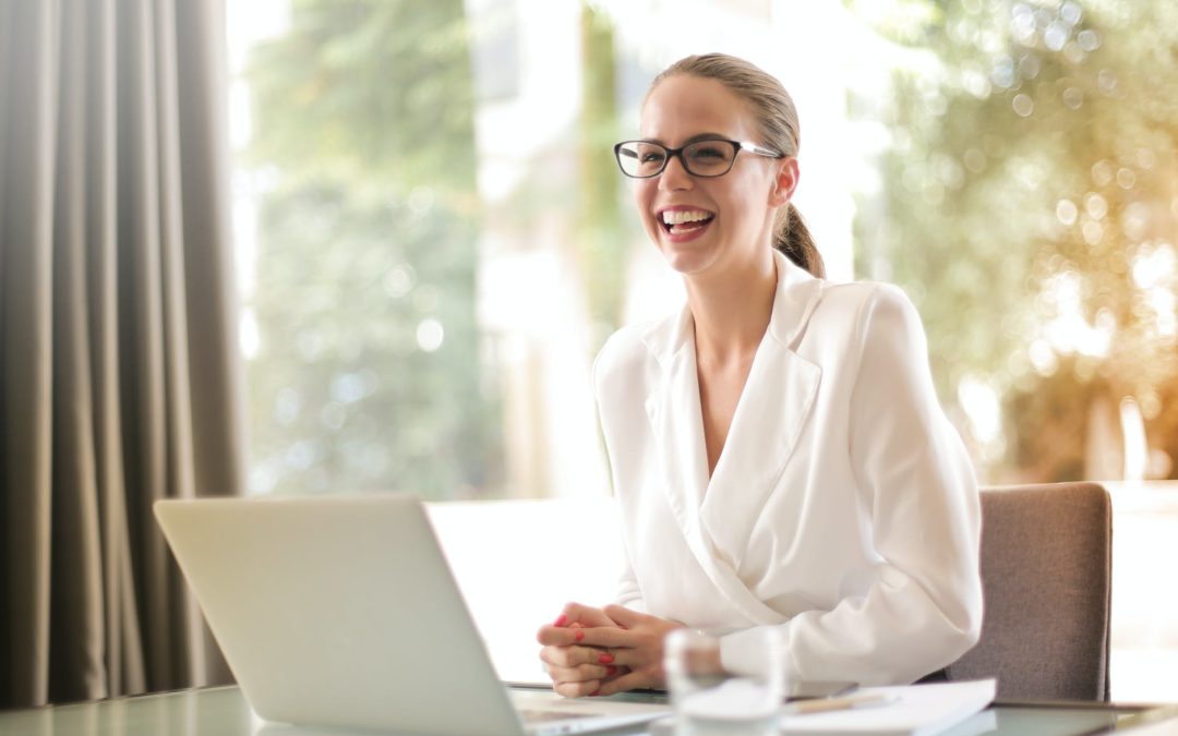 laughing businesswoman working in office with laptop
